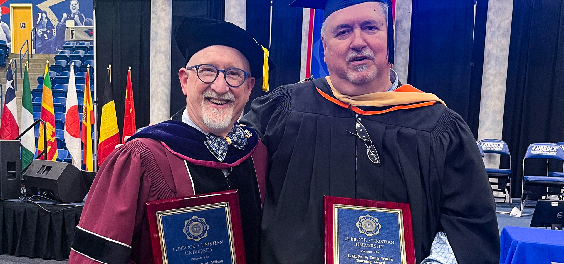 Byron Rogers and Tony Parnell holding their plaque in front of the graduation stage