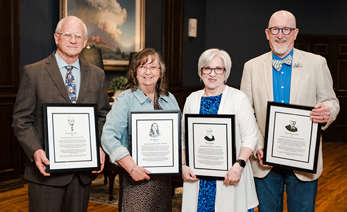 The four retirees holding their plaques from the employee dinner