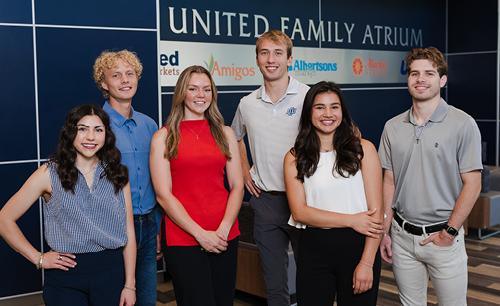 6 students standing in the lobby of the School of Business