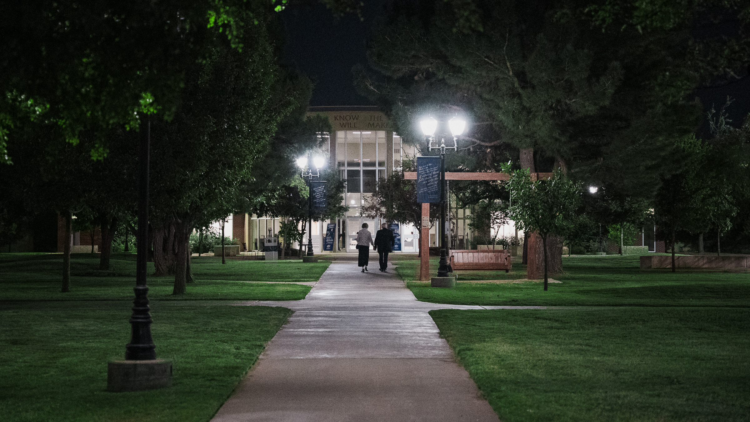 Don with his wife holding hands as they walk down the mall area at night