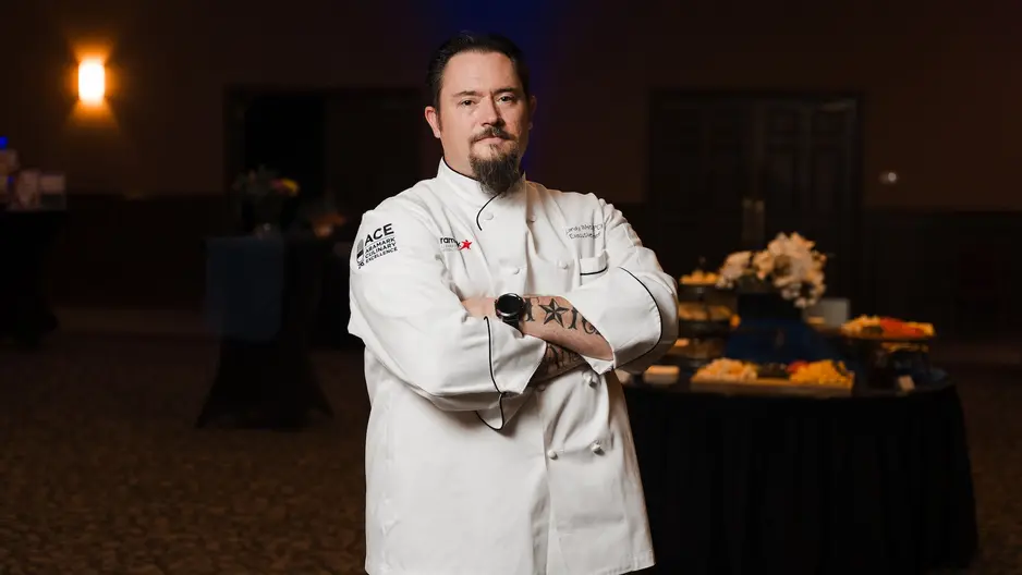 Randy White standing in chef coat with arms crossed in baker conference center