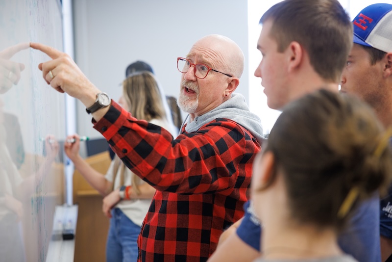 Photograph of Dr. Byron Rogers at the whiteboard with students
