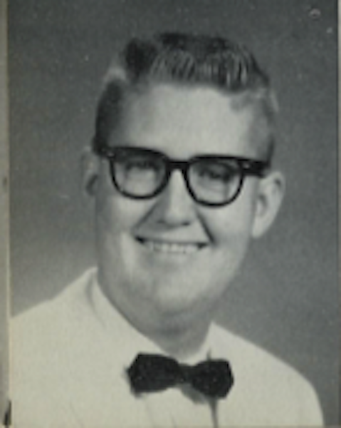 Black-and-white portrait of Lynn Sherrod smiling and wearing a white suit.