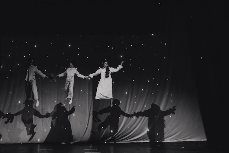 Photograph from the show Peter Pan, where several of the cast are suspended from the ceiling in hidden harnesses and wires